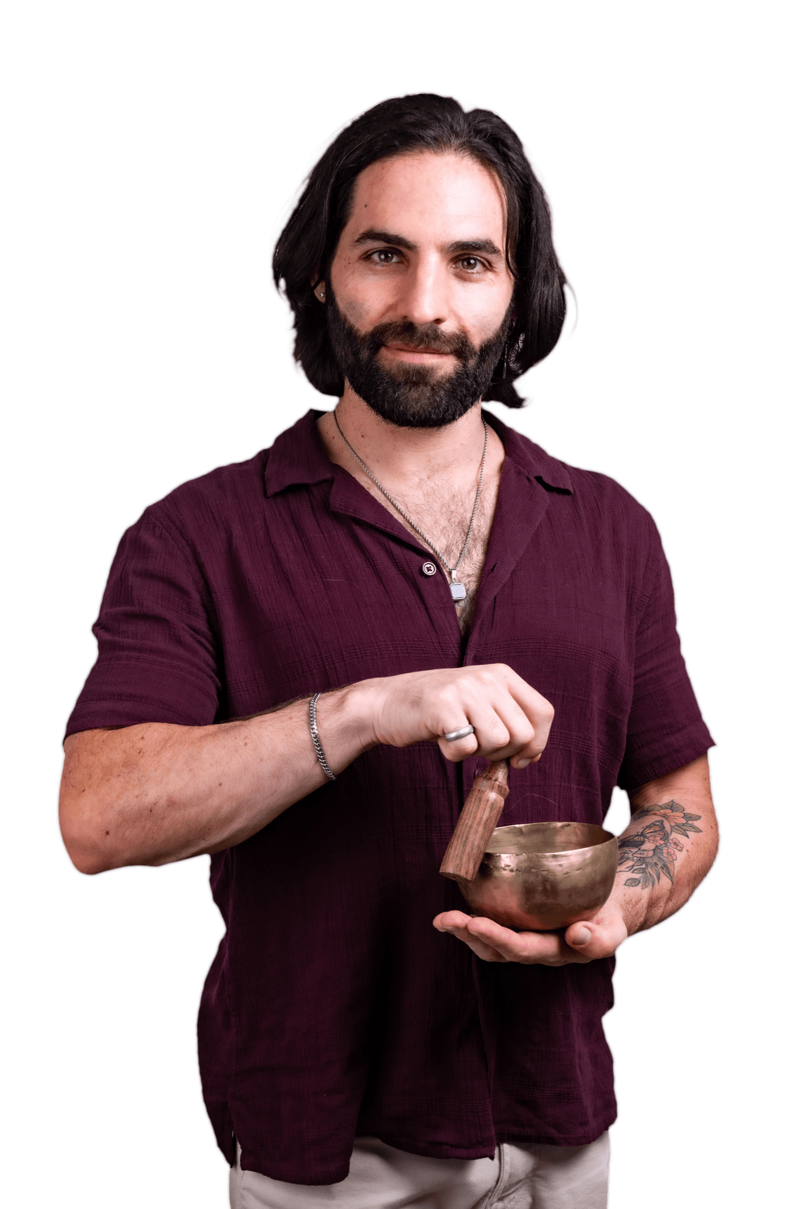 Joseph Buchoff in a deep red shirt, ringing a brass singing bowl with a calm grin